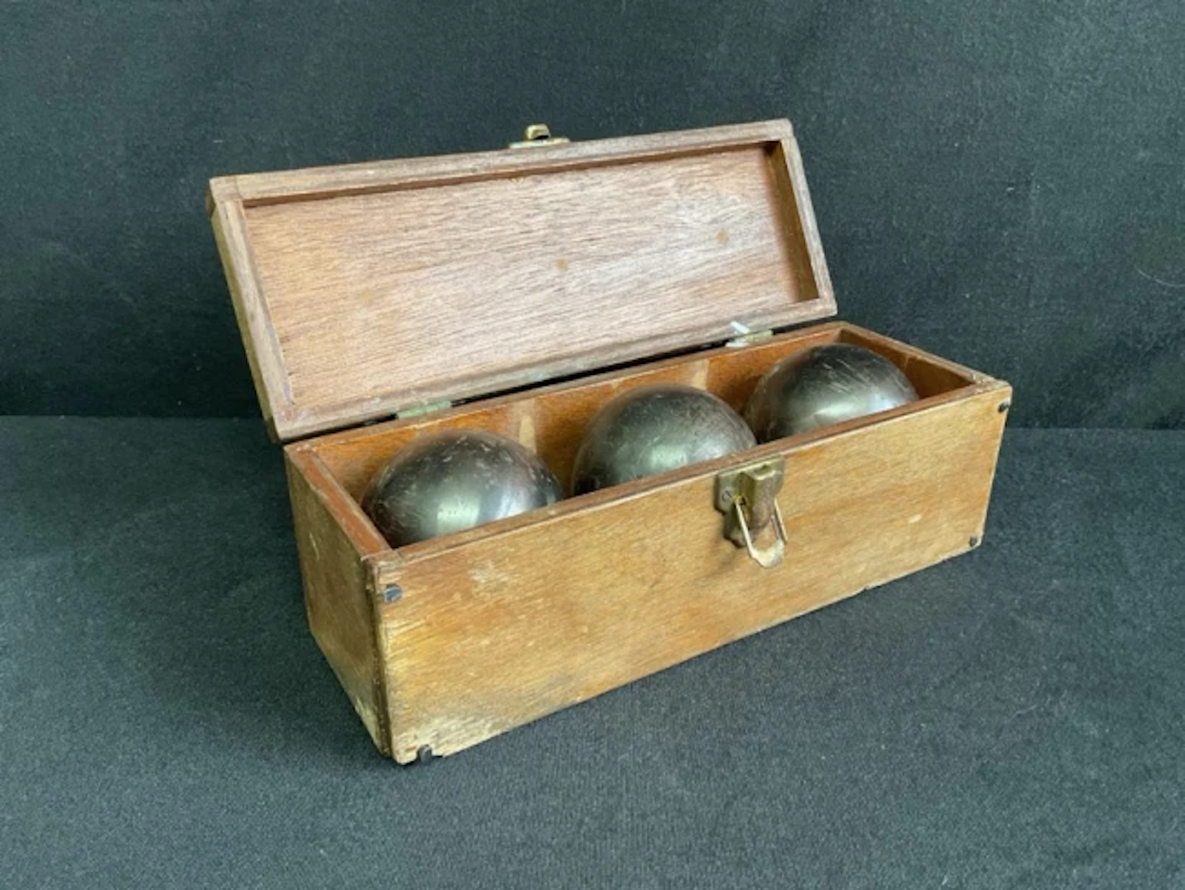 A set of three cast steel French boules in a rectangular brass handled