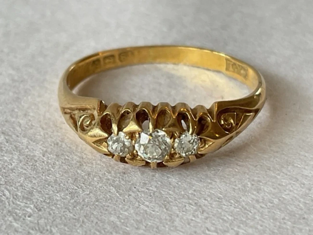 An antique 18ct gold wedding ring with trilogy of old brilliant cut
