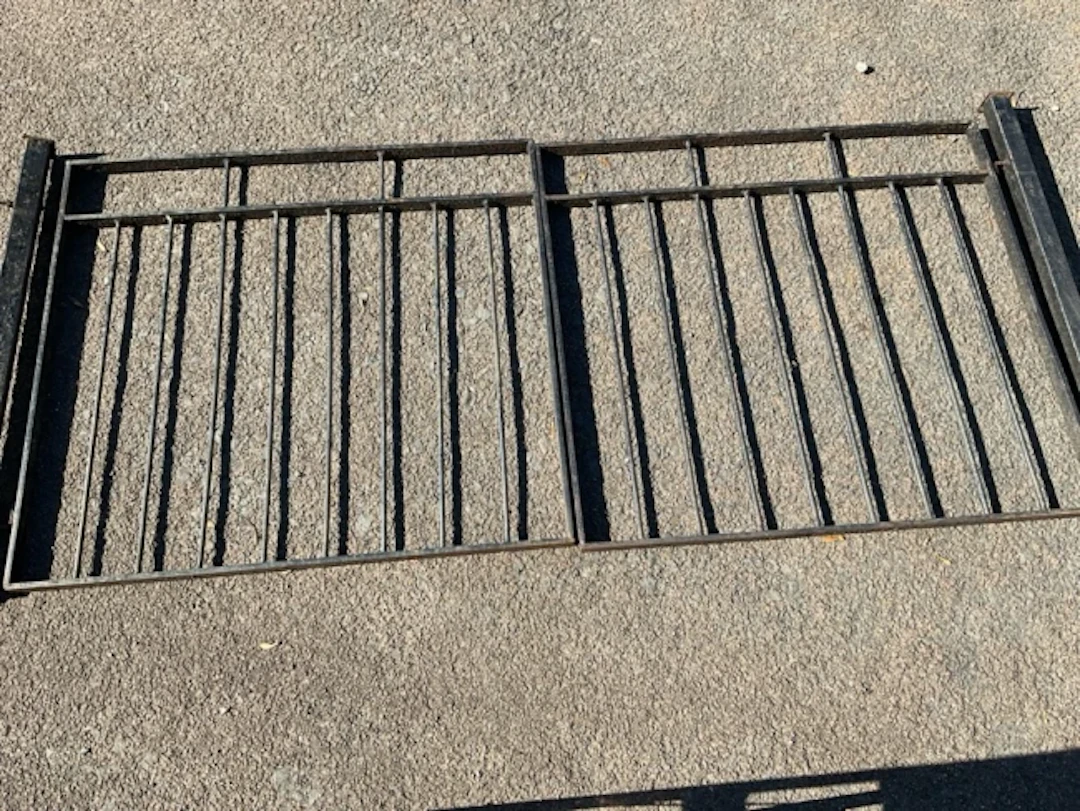 A pair of wrought iron driveway gates with spindles to rectangular