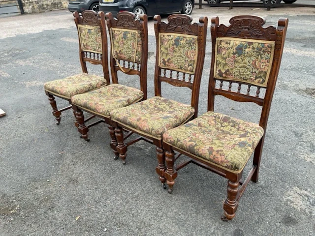 A set of four carved late Victorian dining chairs with shaped crests