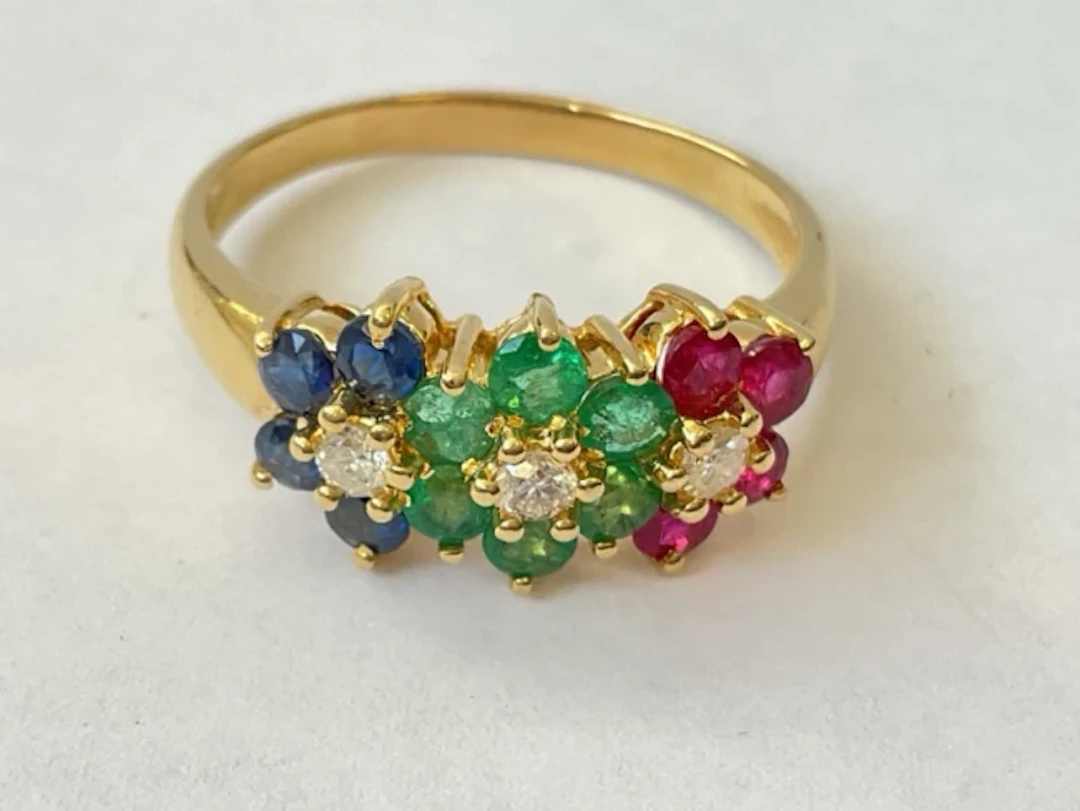 An 18ct gold emerald, ruby & sapphire cluster ring with trio of diamonds