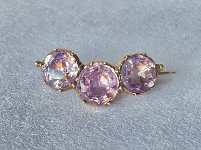 An antique gold brooch set with a trio of circular cut amethysts. (1in)