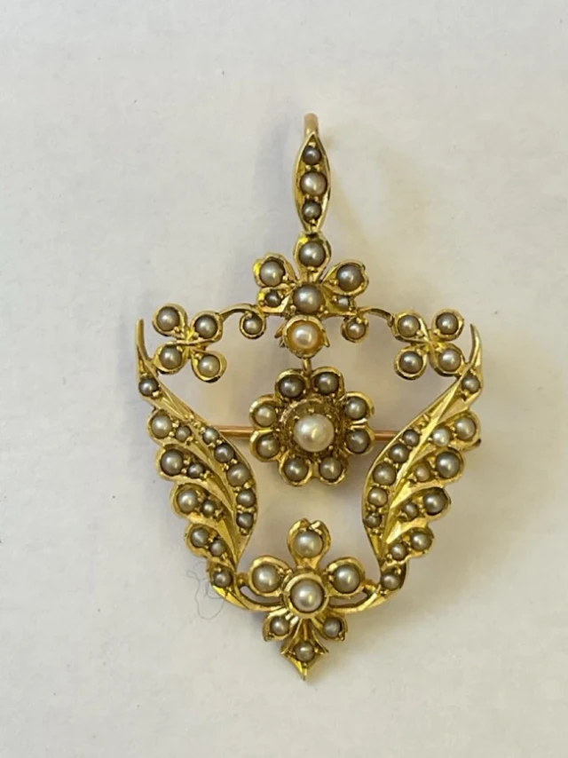 An antique 18ct gold pendant/brooch, the shield shaped floral leaf