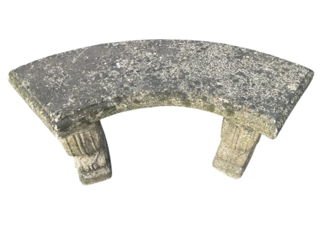 A composition stone garden bench of crescent shape, the moulded slab