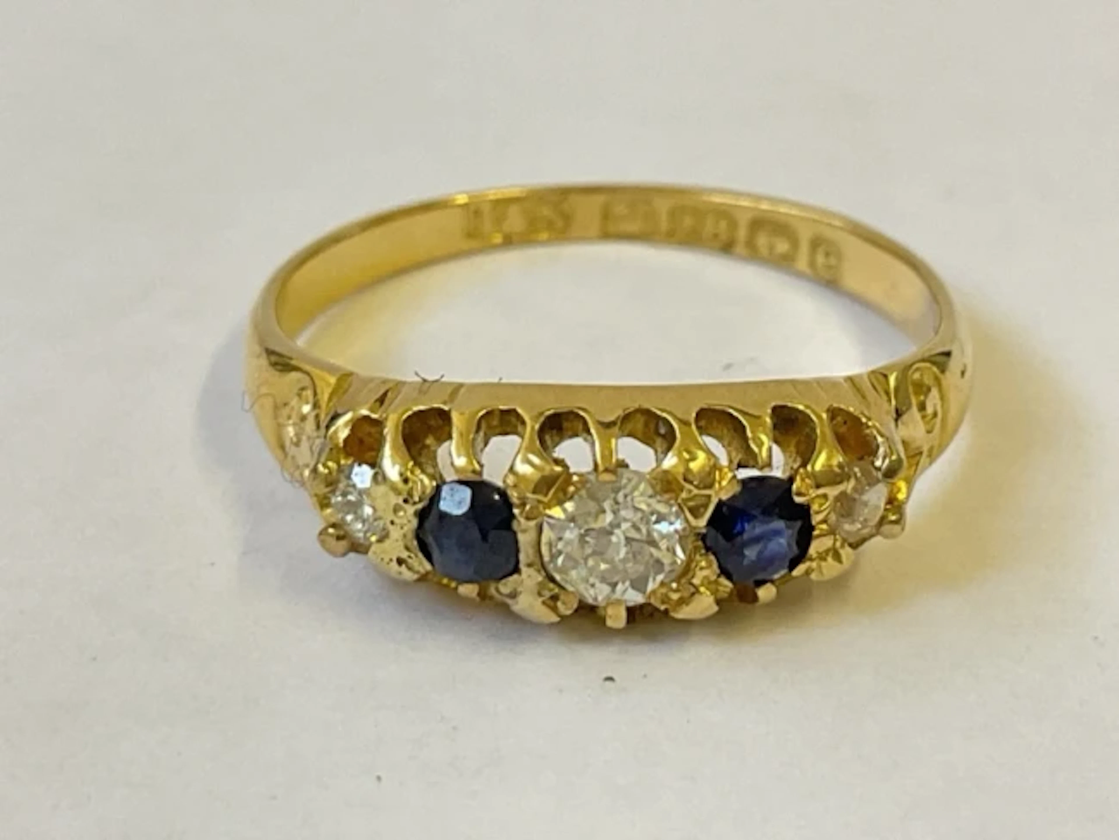 An antique 18ct gold ring with diamond trilogy separated by two sapphires