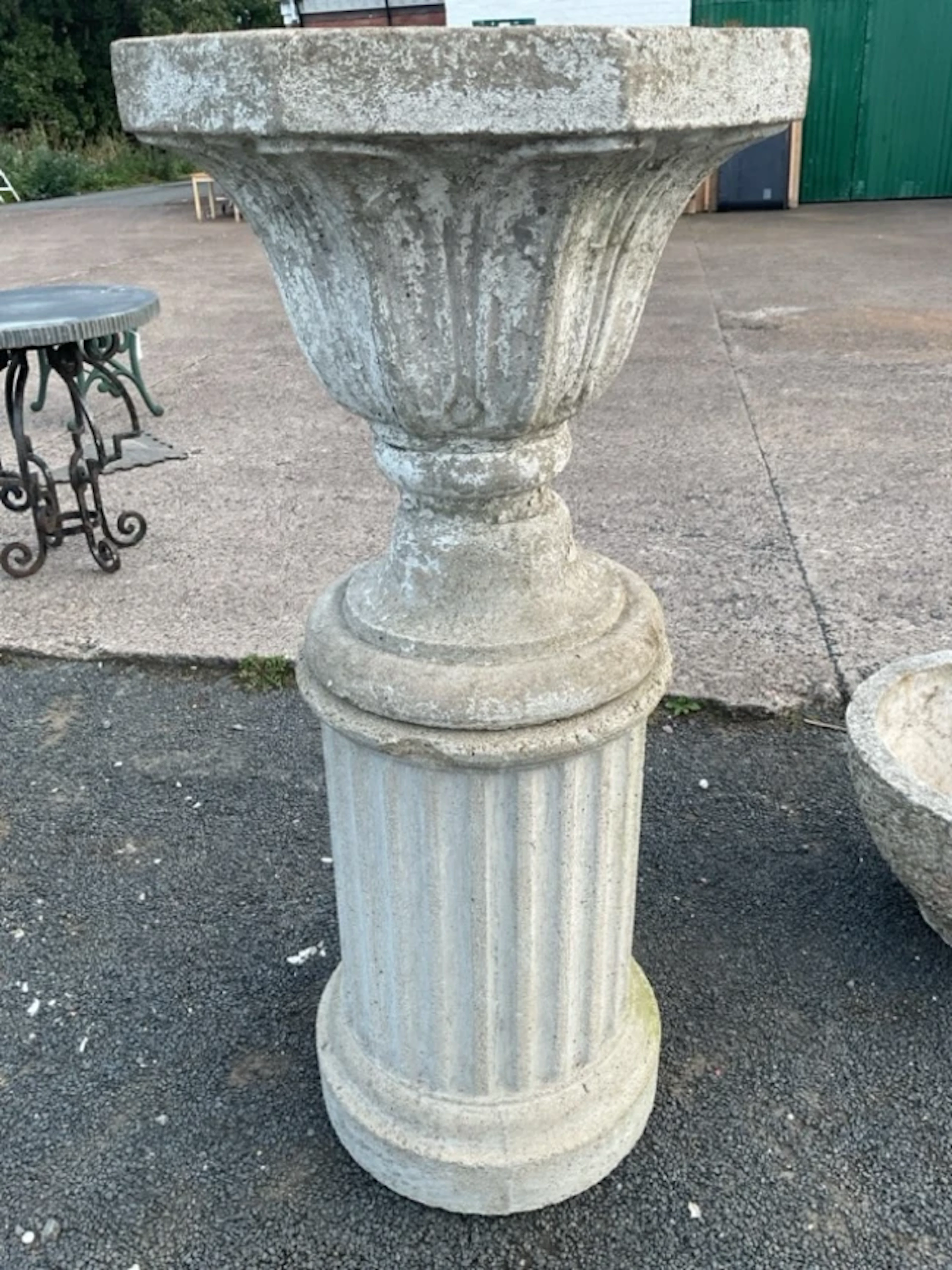 A painted composition stone garden urn on an associated column stand