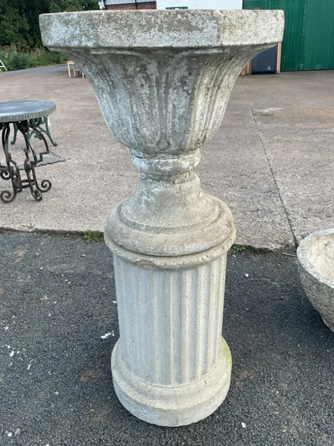 A painted composition stone garden urn on an associated column stand