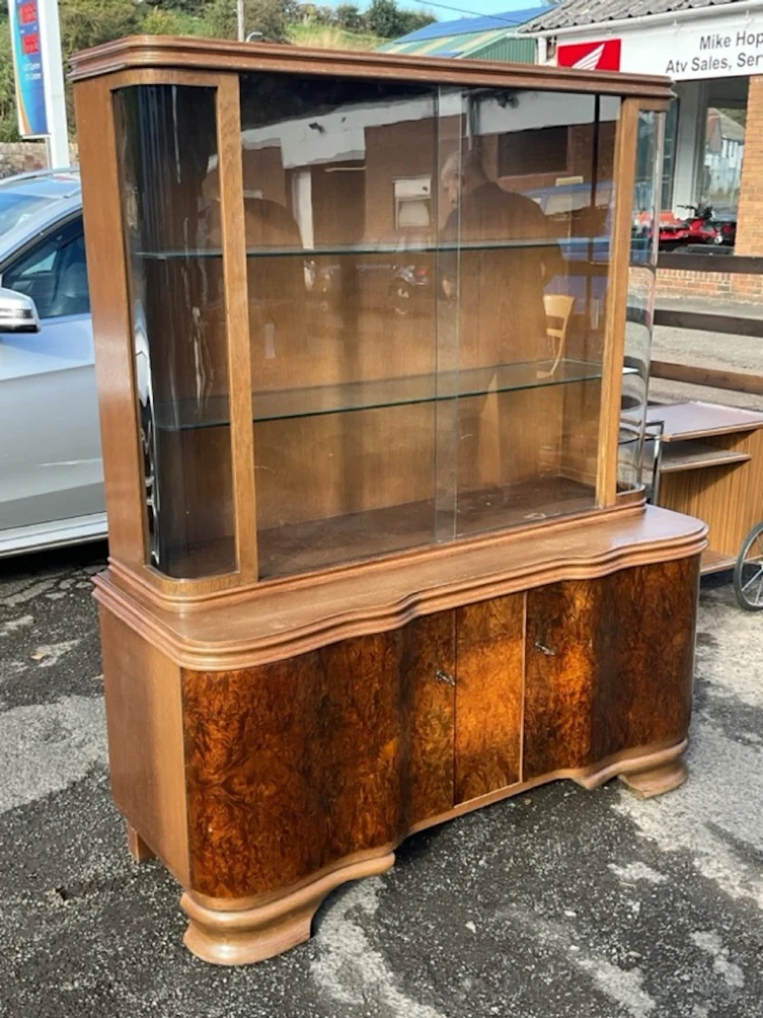A continental walnut display cabinet with rounded glass ends and sliding