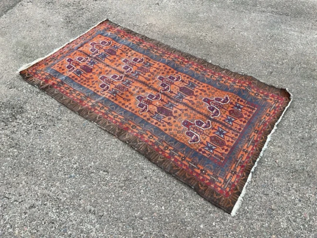 A Baluch wool prayer rug with multiple lantern motifs on an orange