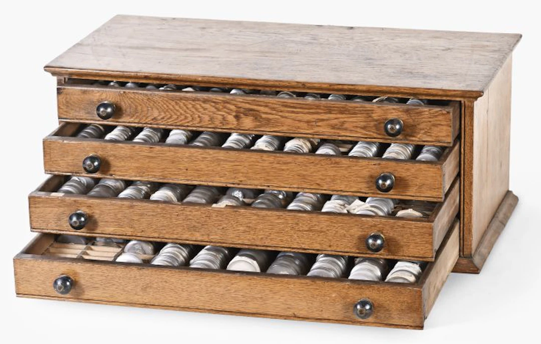 A watchmaker's four drawer oak crystal cabinet with a large inventory