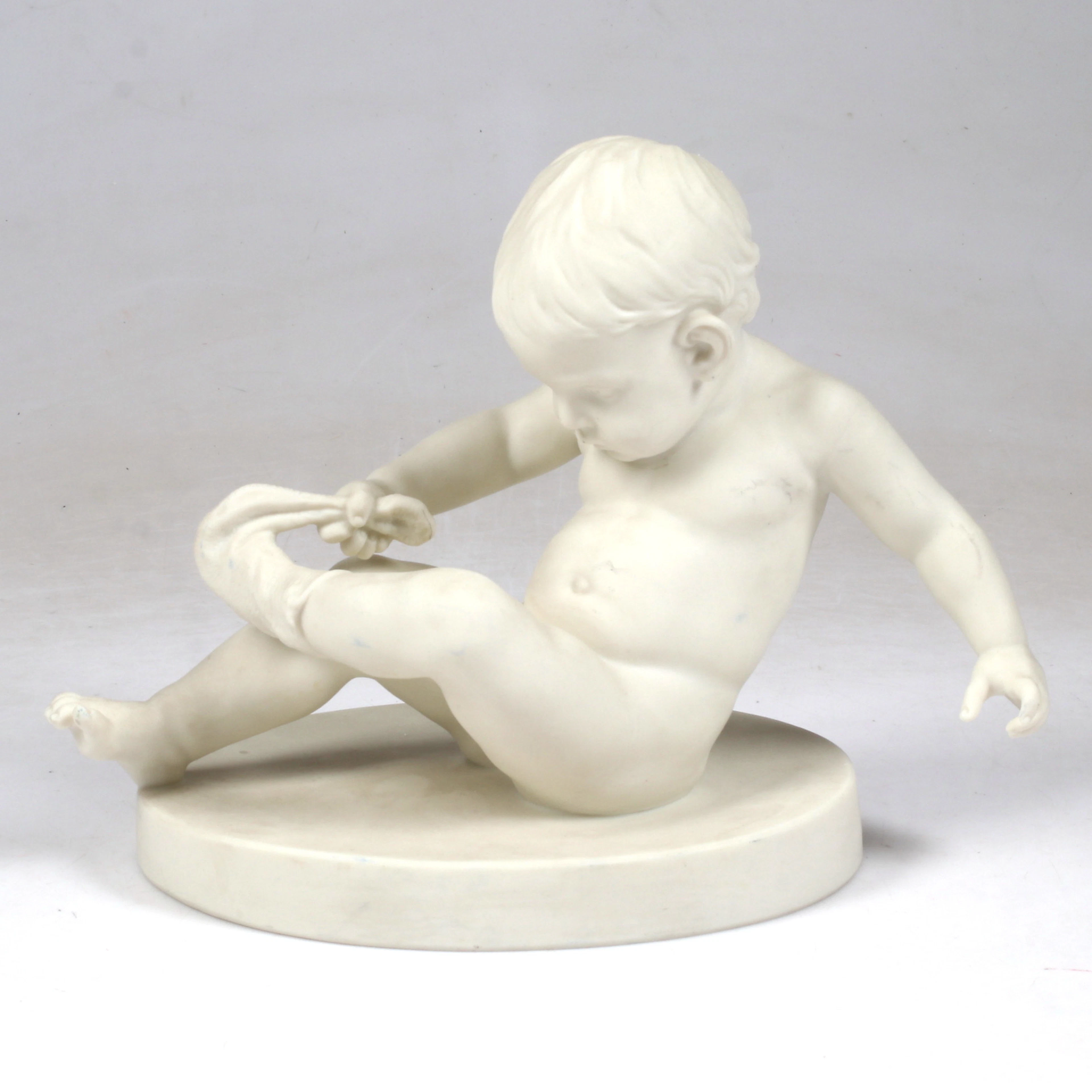 FIGURIN, pojke med strumpa, parian, Gustavsberg, 1921.