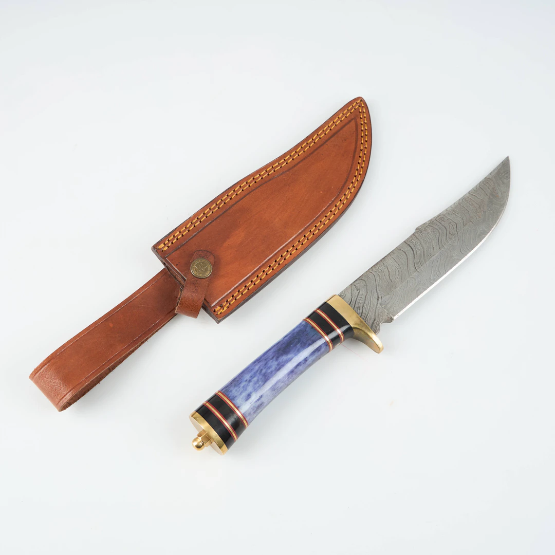 JAKTKNIV, damskusblad, färgat ben, läderbalja.