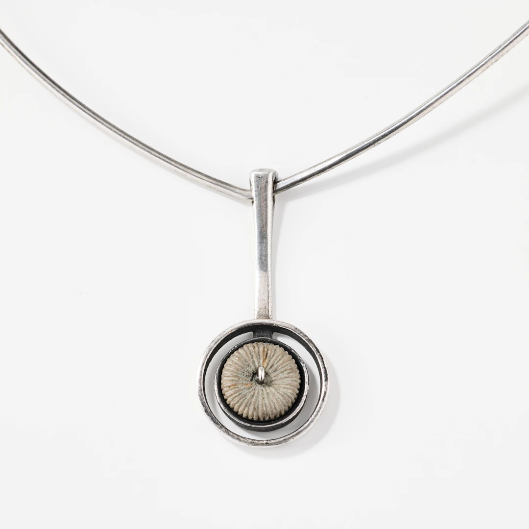 IBE DAHLQVIST. Halsring med hänge, silver och fossiliserad korall