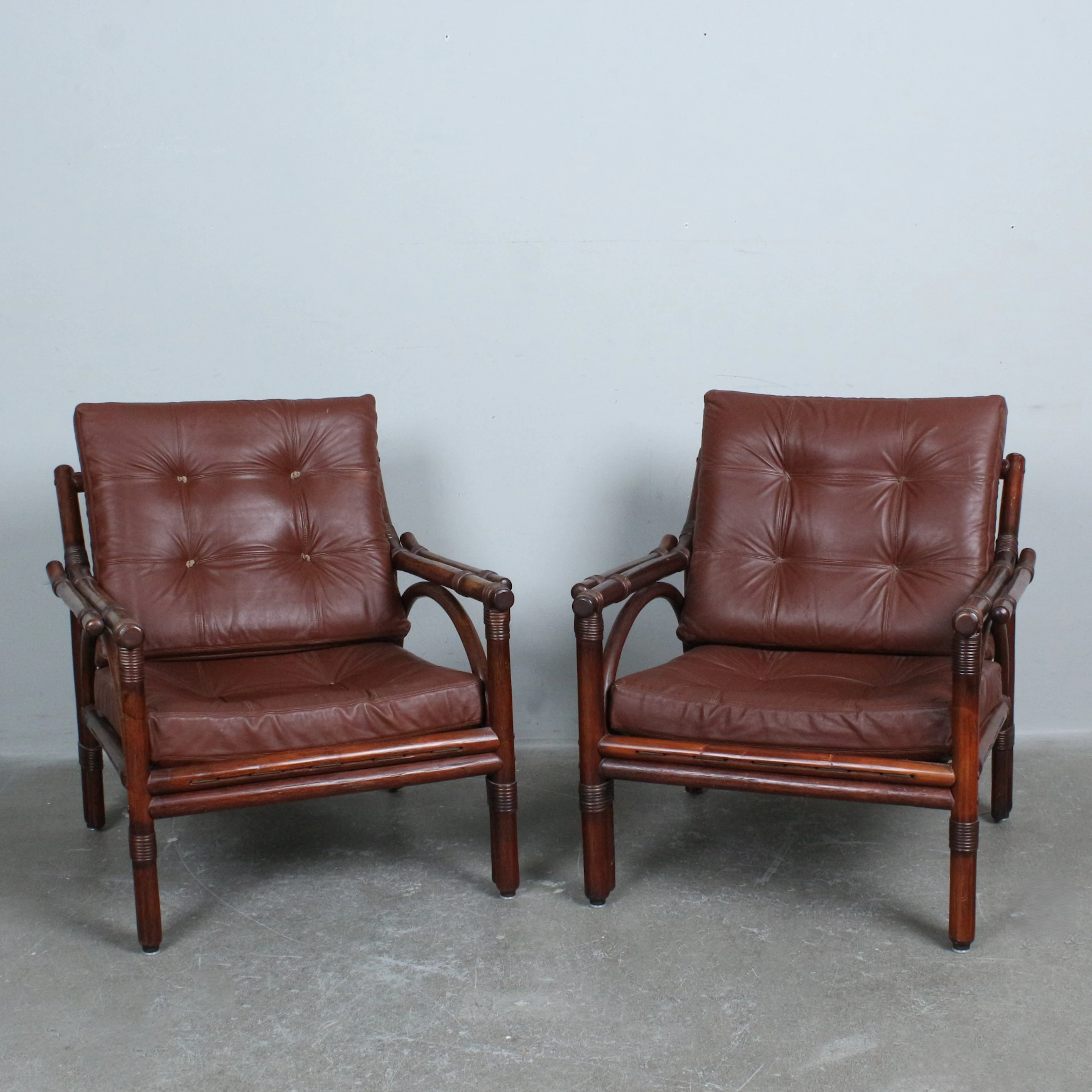 Paar Lounge-Sessel aus gebeiztem Bambus und Rattan mit braunen Lederpolstern.