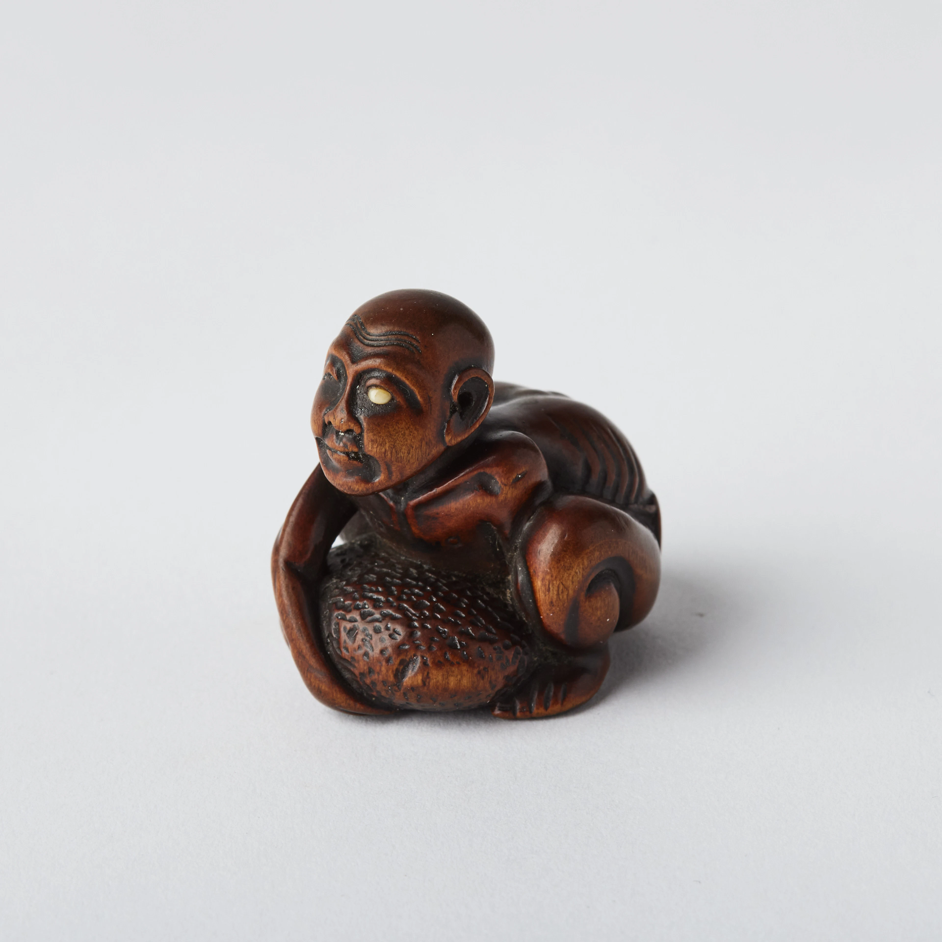 A Japanese Wood Netsuke of a Blind Masseur Lifting a Chikaraishi.