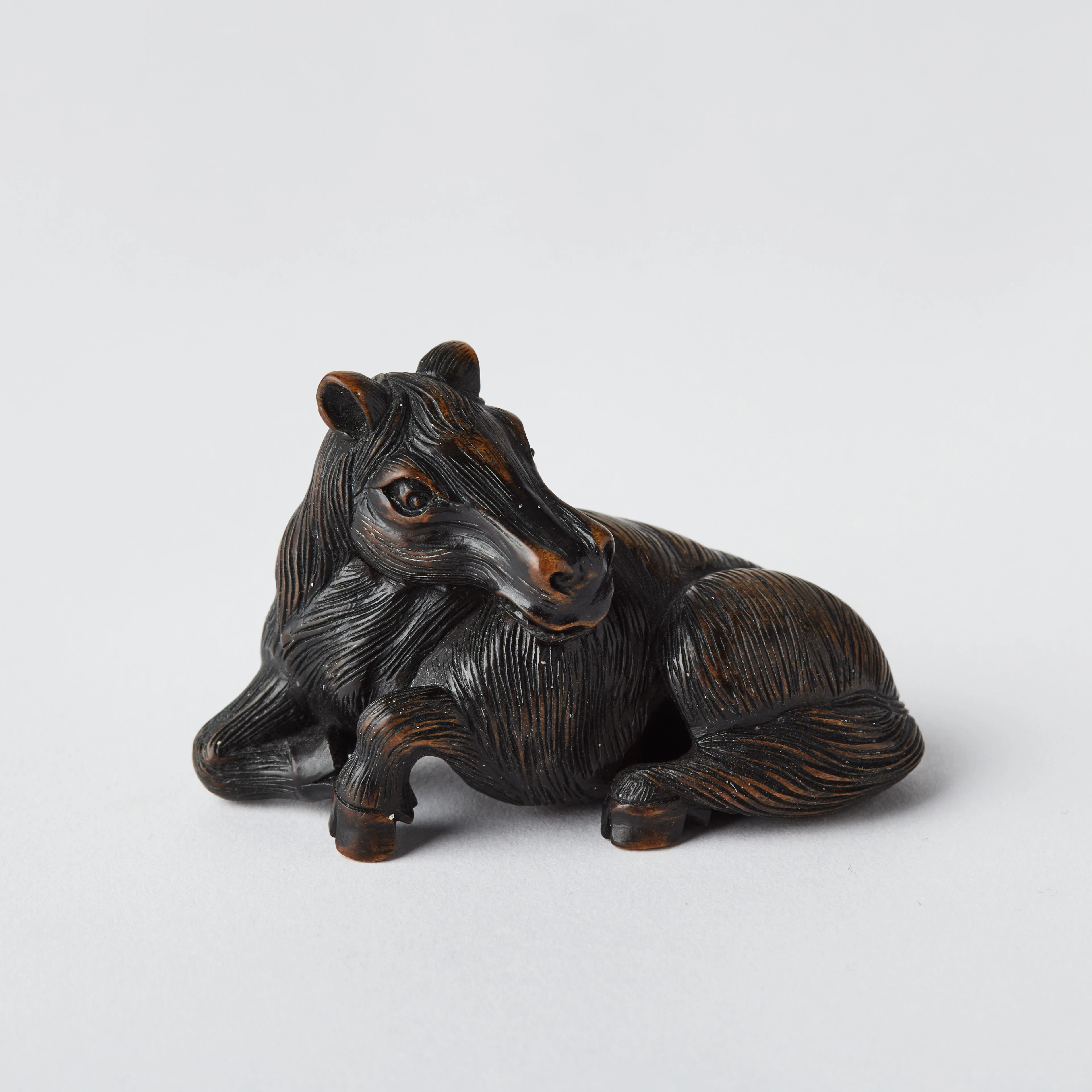 A Japanese Wood Netsuke of a Reclining Horse.
