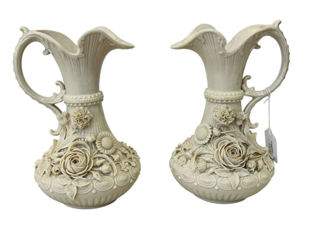 Pair of Belleek flower encrusted ewers, black stamp, 23cm.