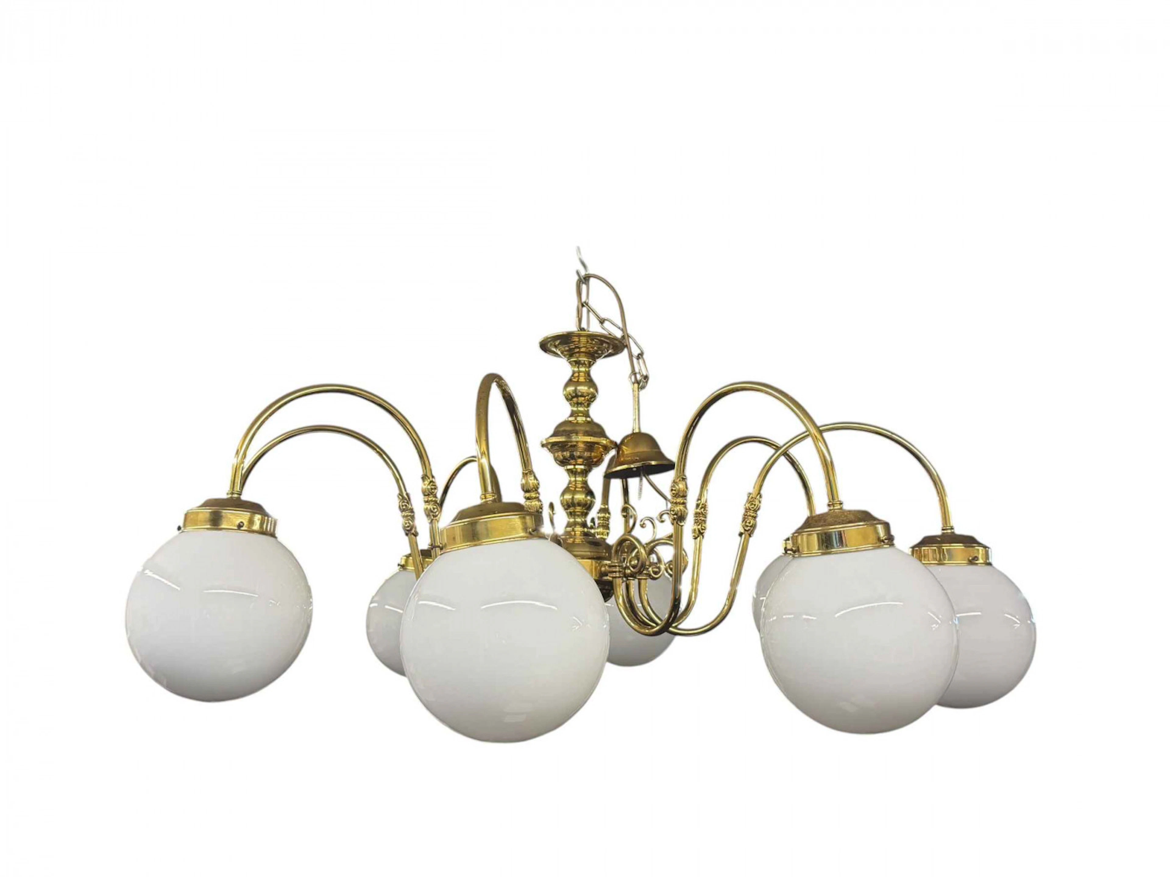 Ornate brass eight branch chandelier with opaque glass globe shades.
