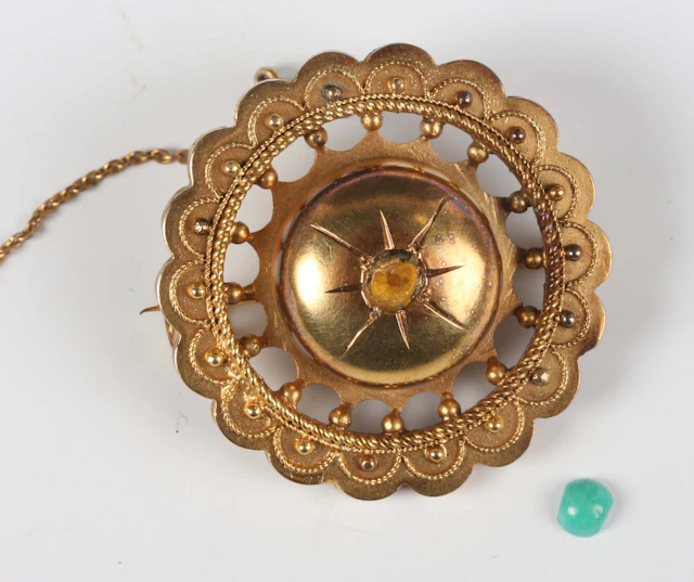 A Victorian gold brooch of shaped circular form with applied bead