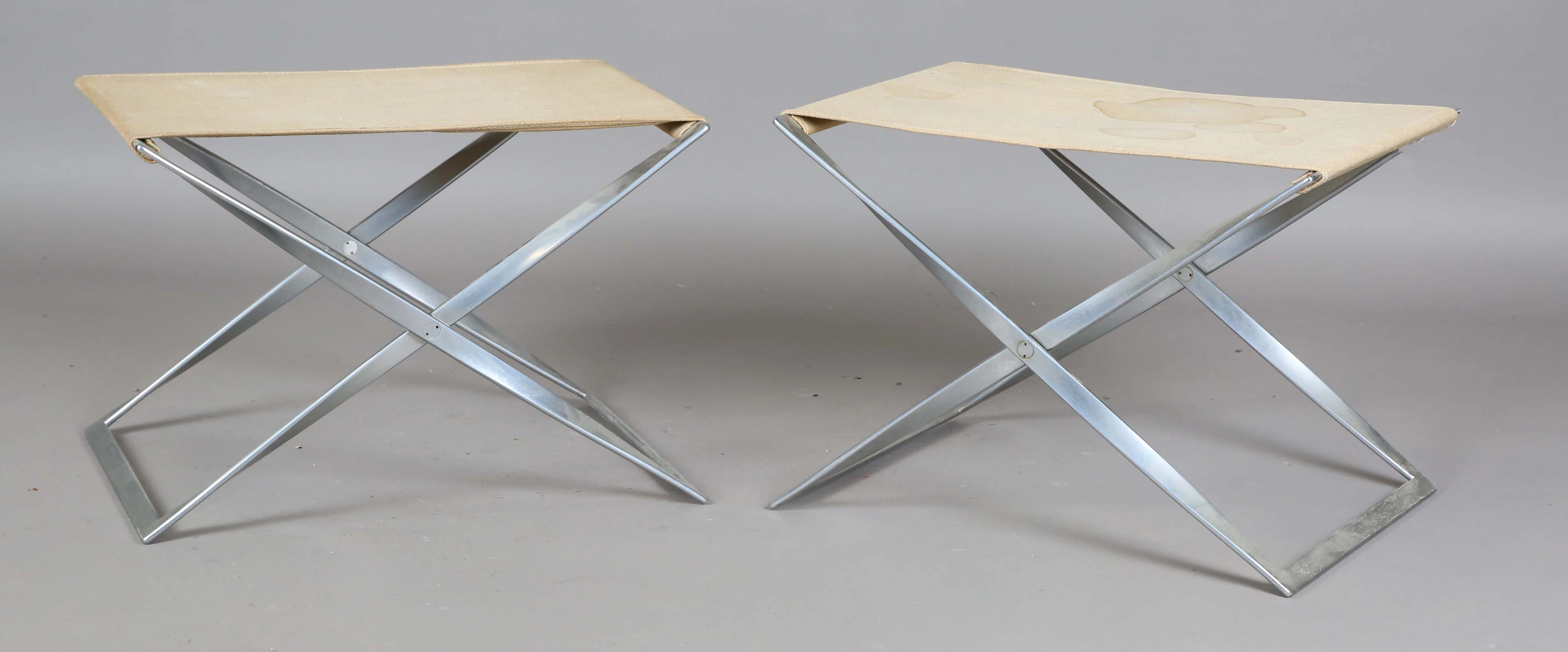 A pair of brushed steel PK91 model folding stools, designed by Poul