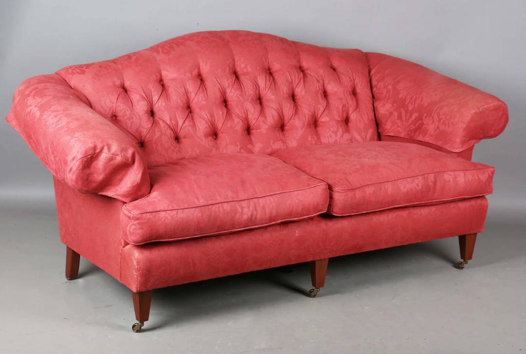 A modern three-seat sofa, upholstered in buttoned raspberry cotton