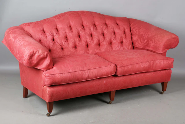 A modern three-seat sofa, upholstered in buttoned raspberry cotton