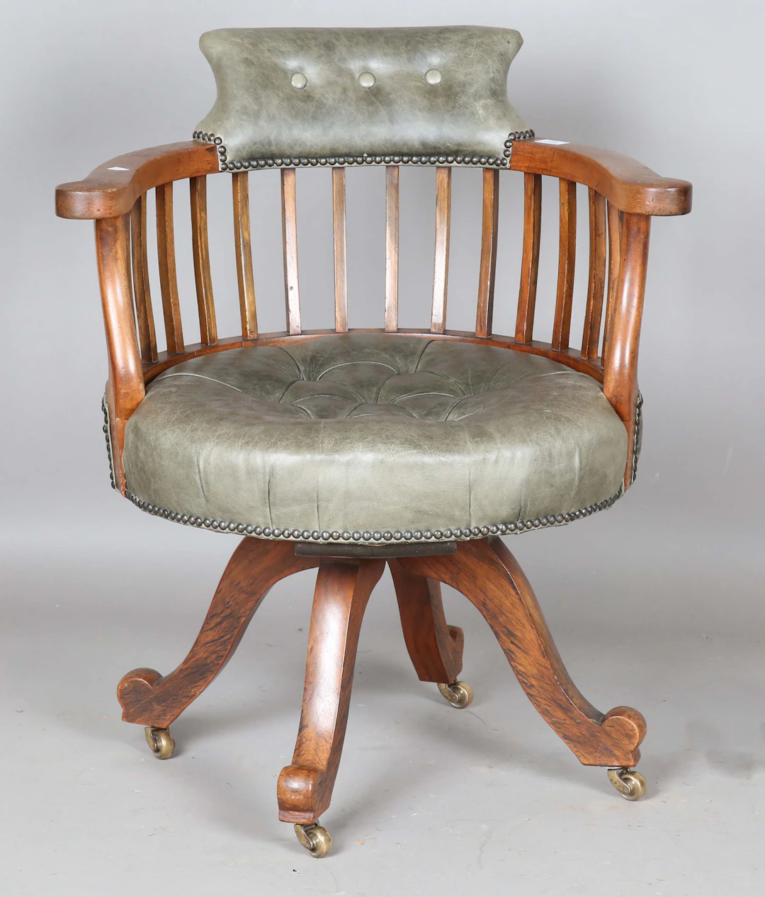 An Edwardian walnut revolving desk chair, upholstered in buttoned