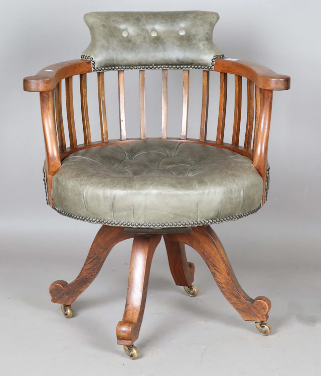 An Edwardian walnut revolving desk chair, upholstered in buttoned