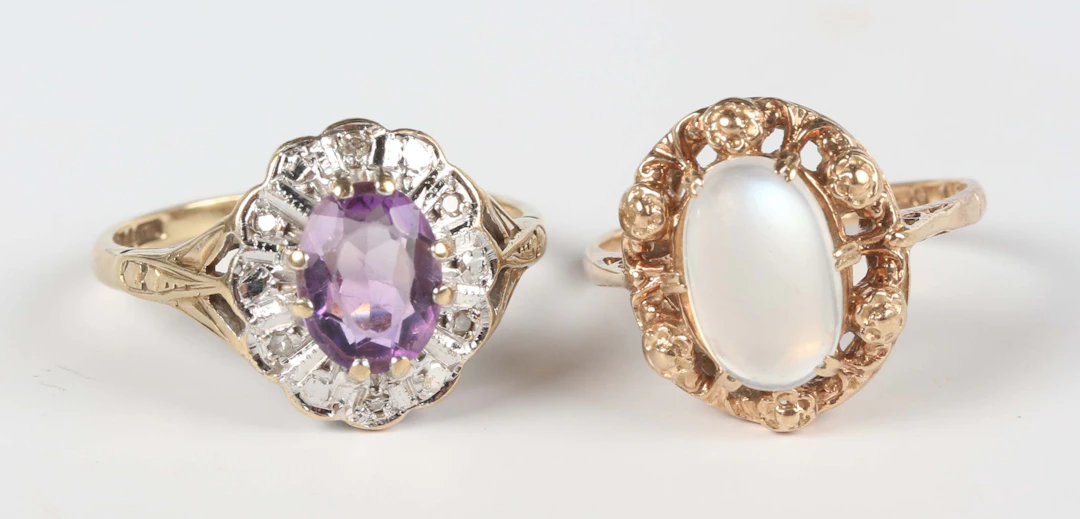 A 9ct gold ring, claw set with an oval moonstone within a floral surround