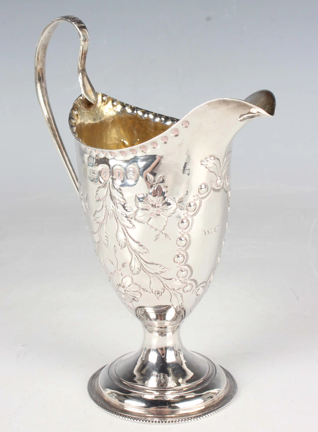 A George III silver cream jug of elongated ovoid form with beaded