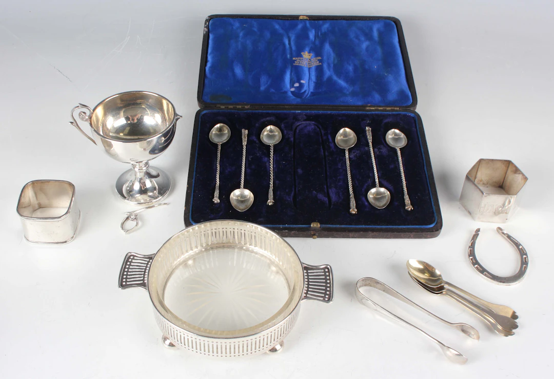 A George V silver circular butter dish with pierced sides, flanked