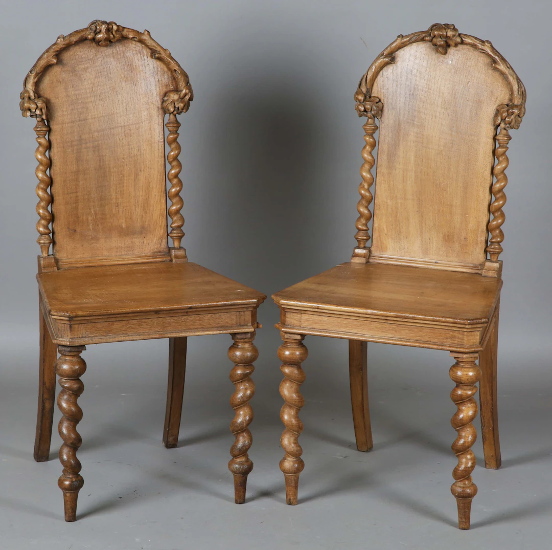 A pair of late 19th century walnut hall chairs, the backs carved with