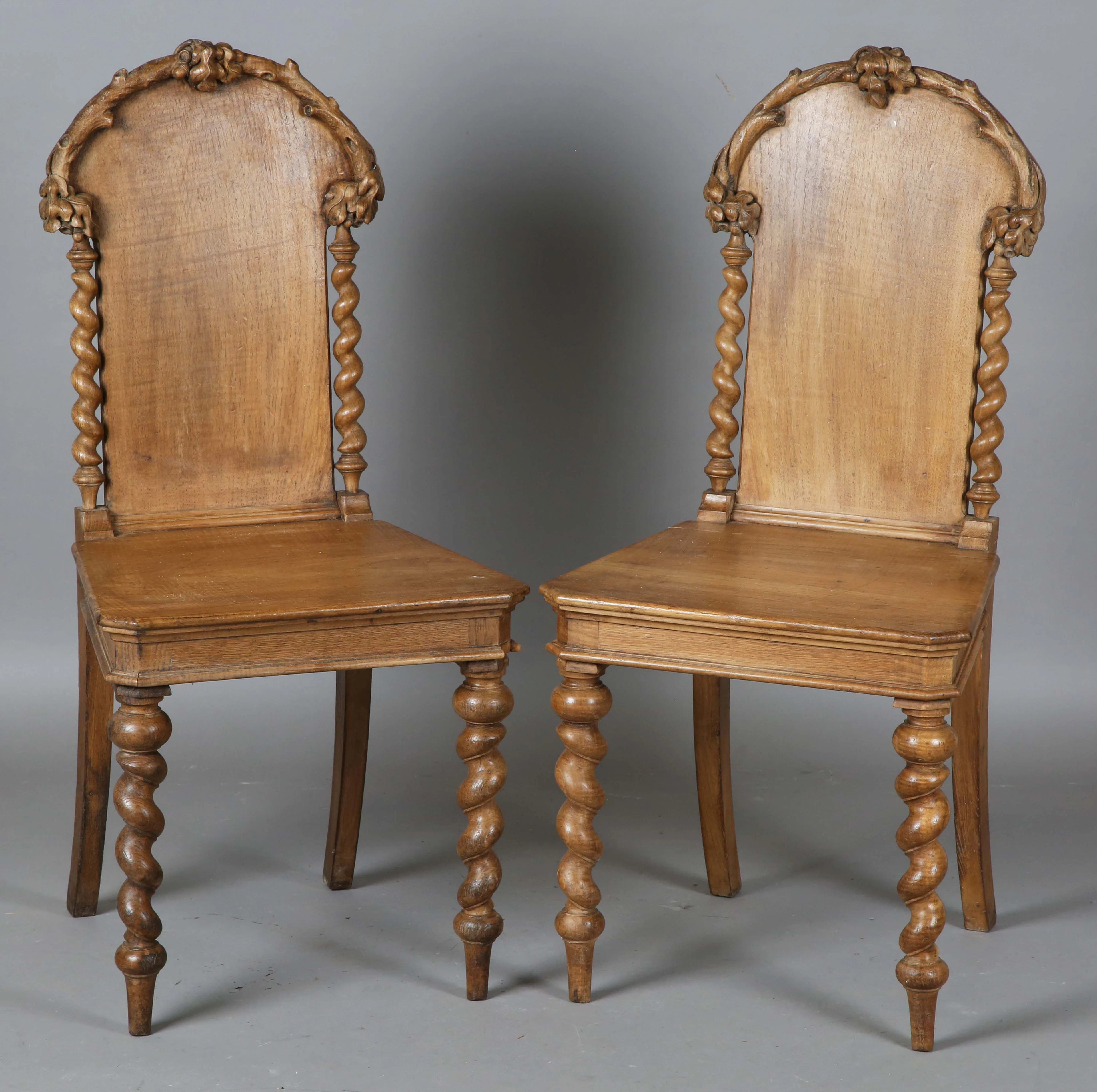 A pair of late 19th century walnut hall chairs, the backs carved with