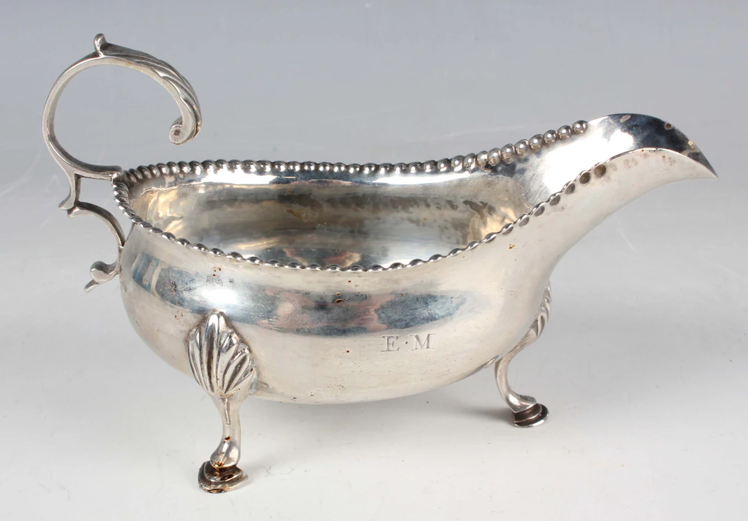 A George III silver sauceboat with foliate-capped flying scroll handle