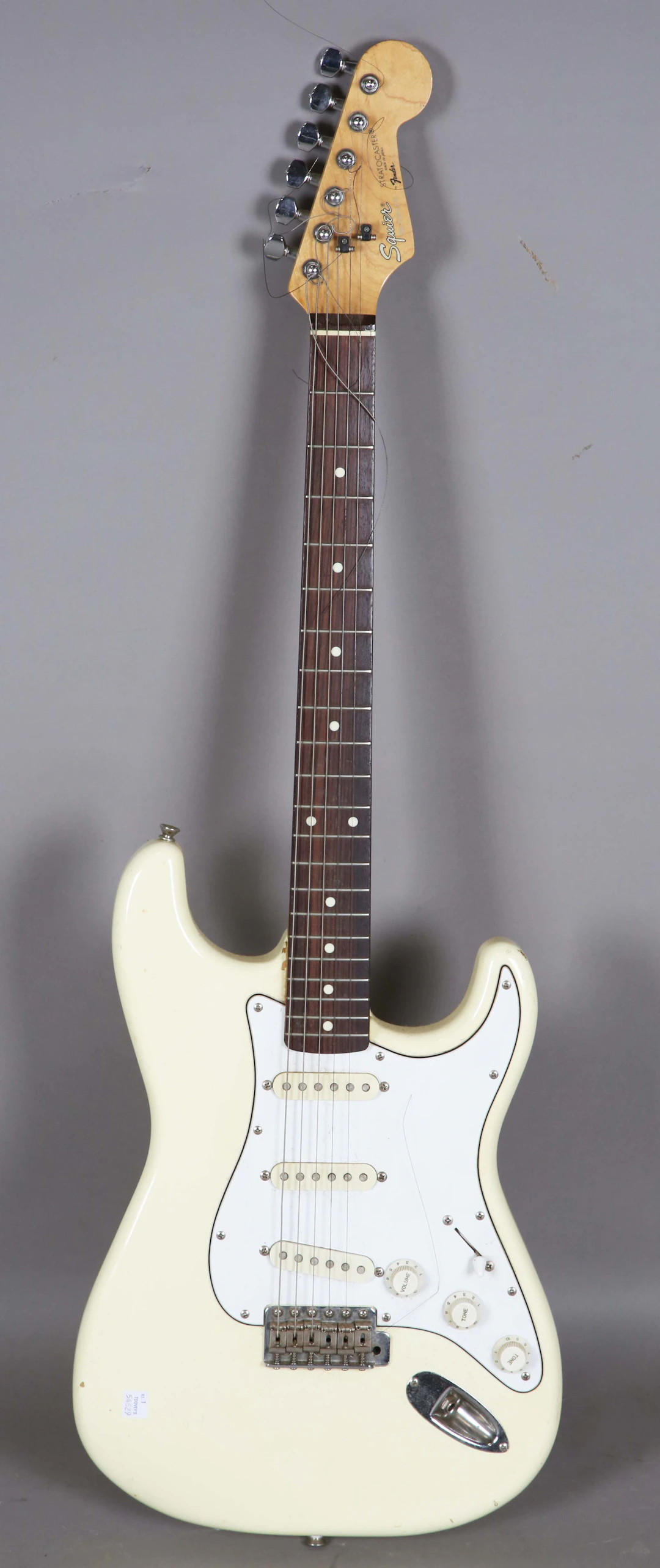 A Squier Stratocaster electric guitar with cream body, the headstock