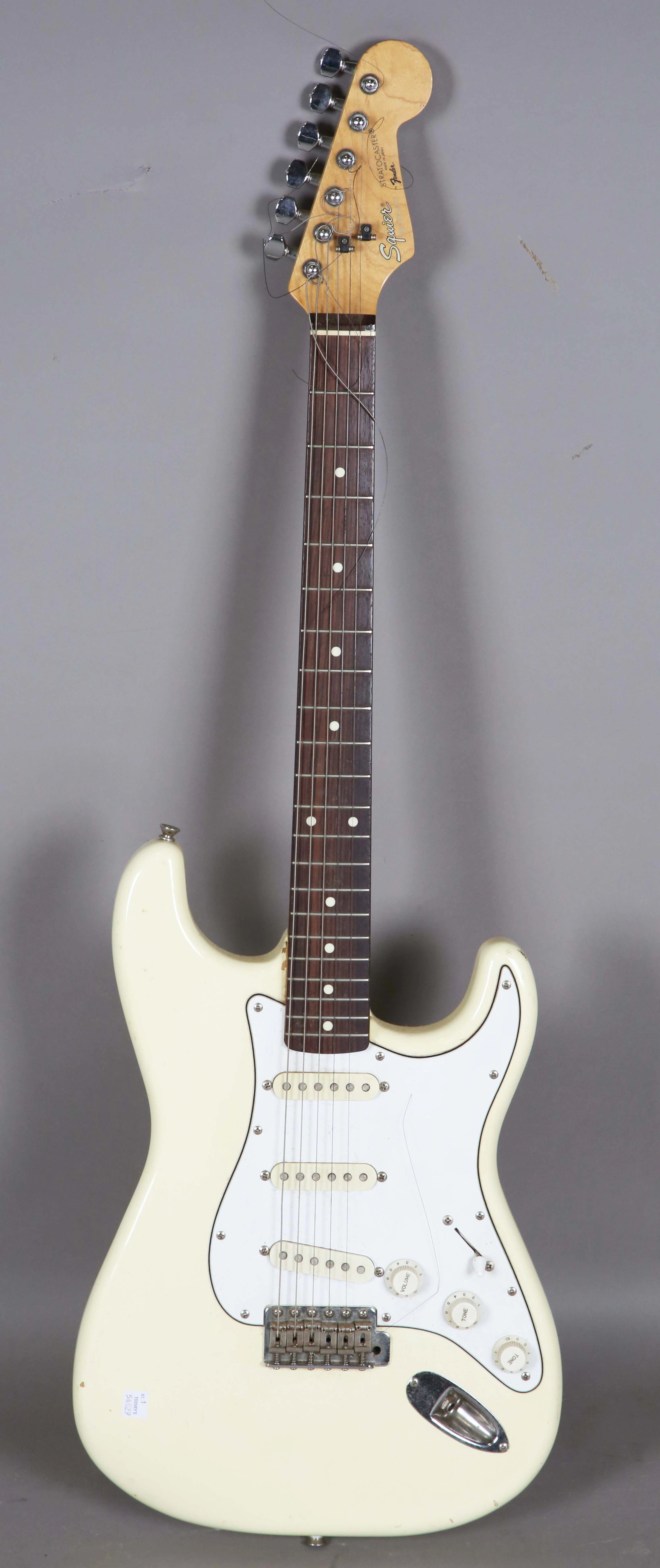 A Squier Stratocaster electric guitar with cream body, the headstock