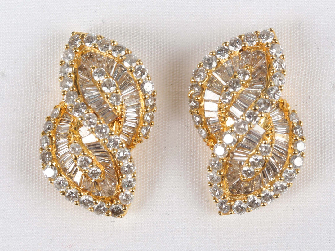 A pair of gold and diamond earrings, each in a twist design, mounted
