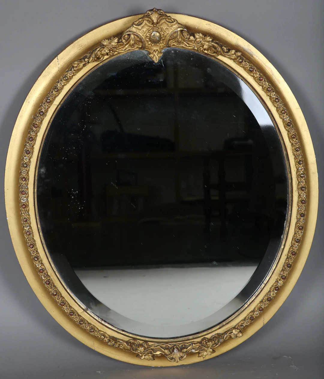A late Victorian gilt gesso oval wall mirror, the deep bevelled plate