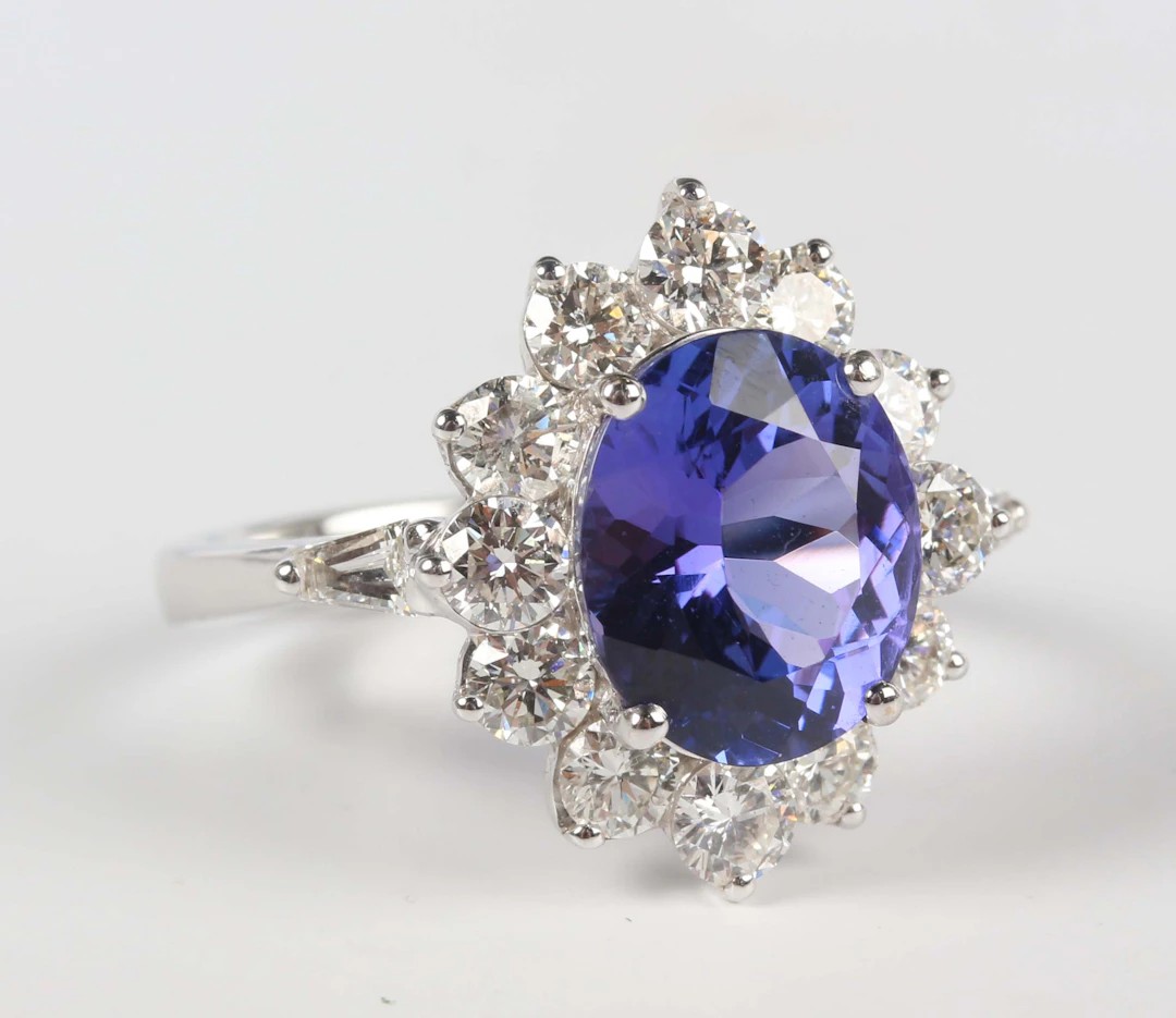 A white gold, tanzanite and diamond oval cluster ring, claw set with