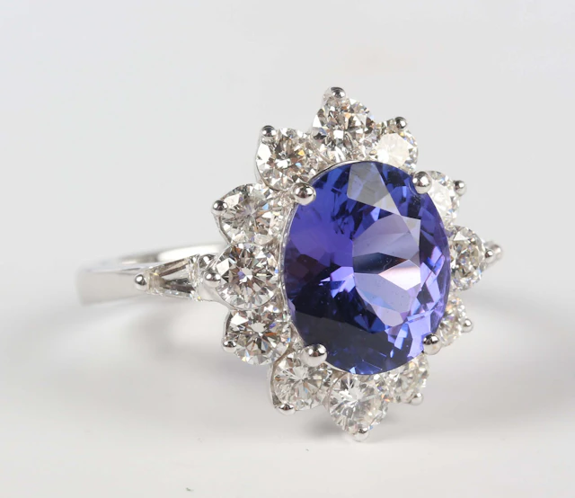 A white gold, tanzanite and diamond oval cluster ring, claw set with