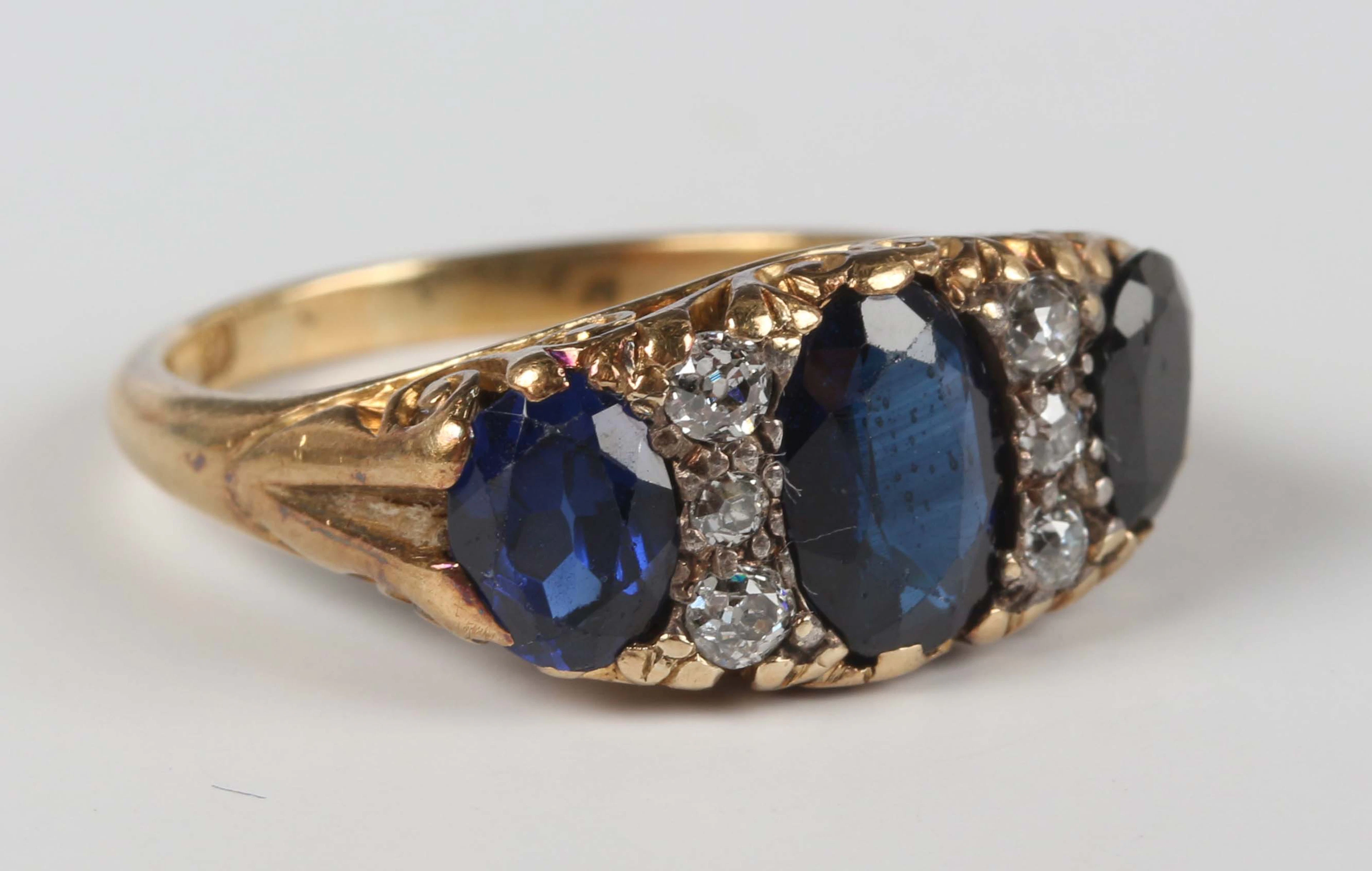 A gold, synthetic sapphire and diamond ring, mounted with three oval