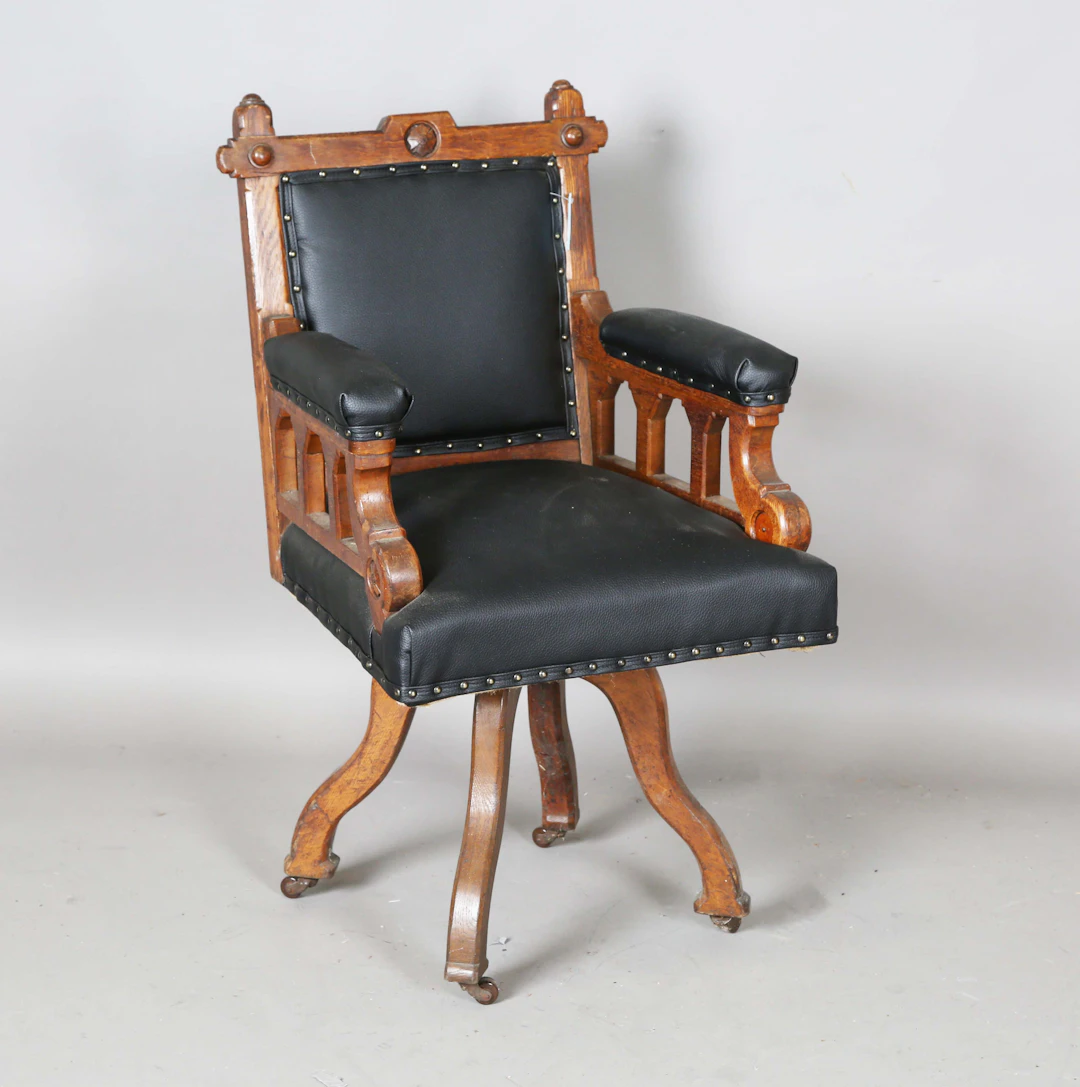 A late Victorian Gothic Revival oak framed revolving desk chair, upholstered