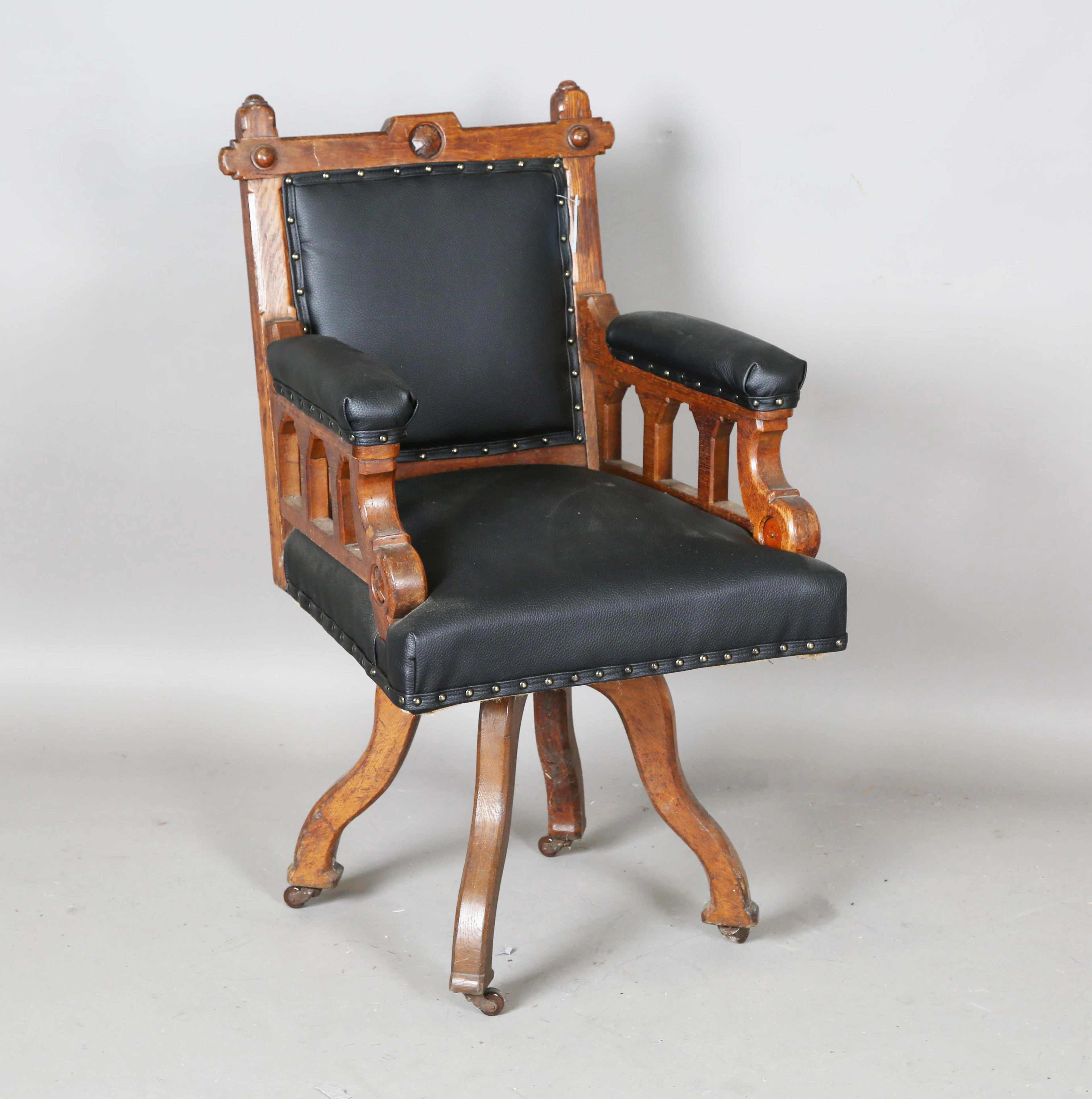 A late Victorian Gothic Revival oak framed revolving desk chair, upholstered