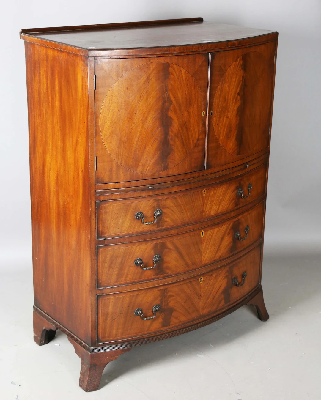An early 20th century Sheraton style mahogany bowfront tallboy cabinet