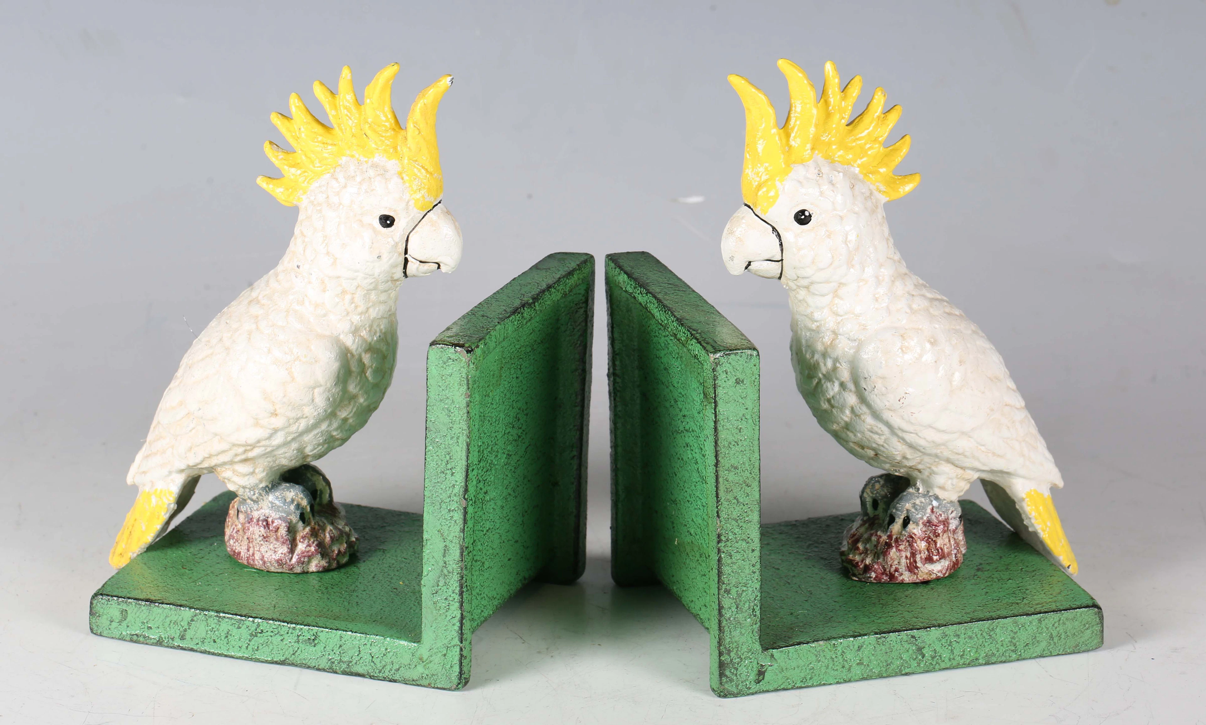 A pair of cold painted cast iron bookends, each with a cockatoo mount