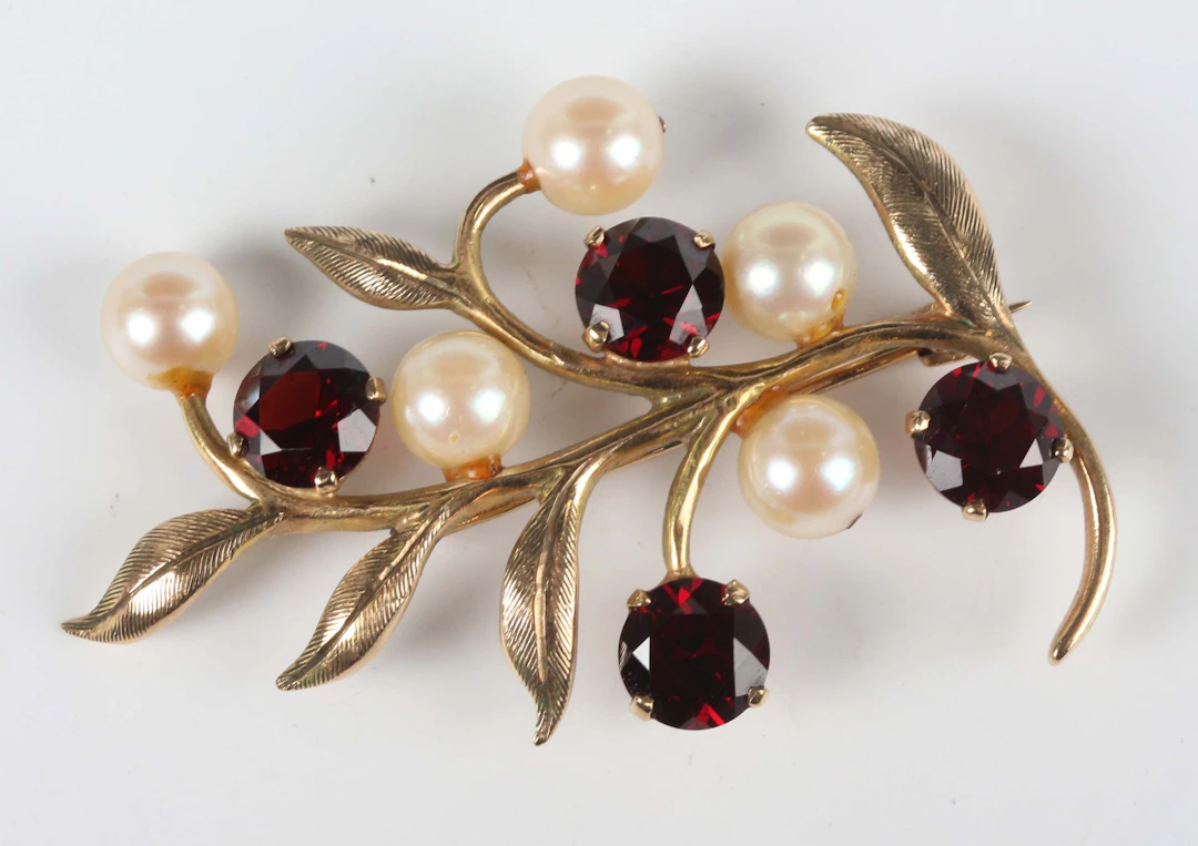 A 9ct gold, garnet and cultured pearl brooch in a foliate spray design