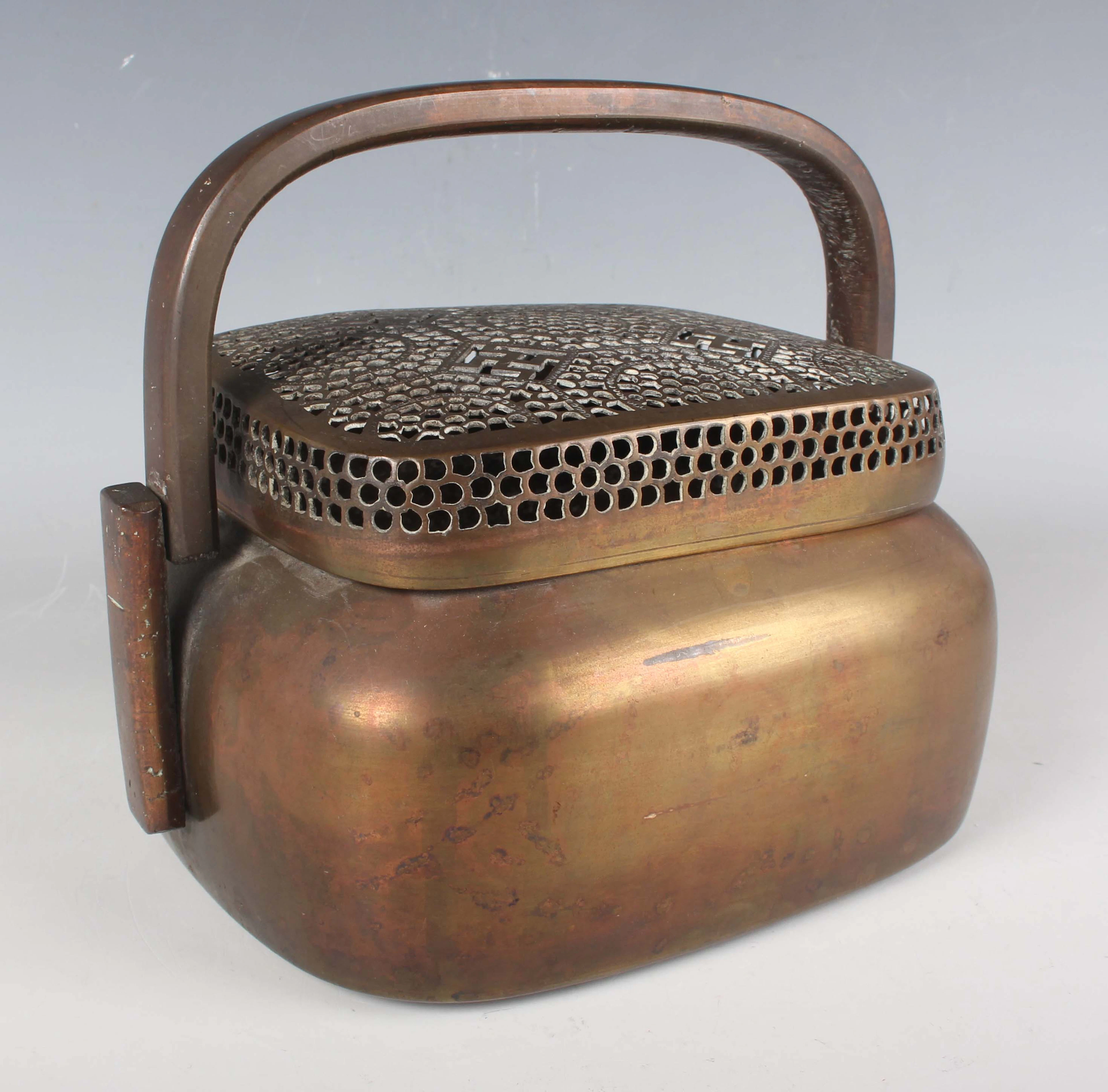 A Chinese copper alloy handwarmer and cover, Qing dynasty, of rounded