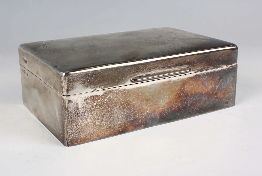 A George V silver rectangular cigarette box, the hinged lid name engraved