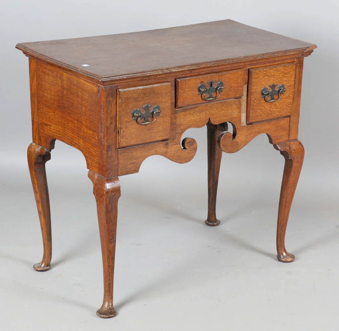 A George III oak lowboy, fitted with three drawers, on cabriole legs