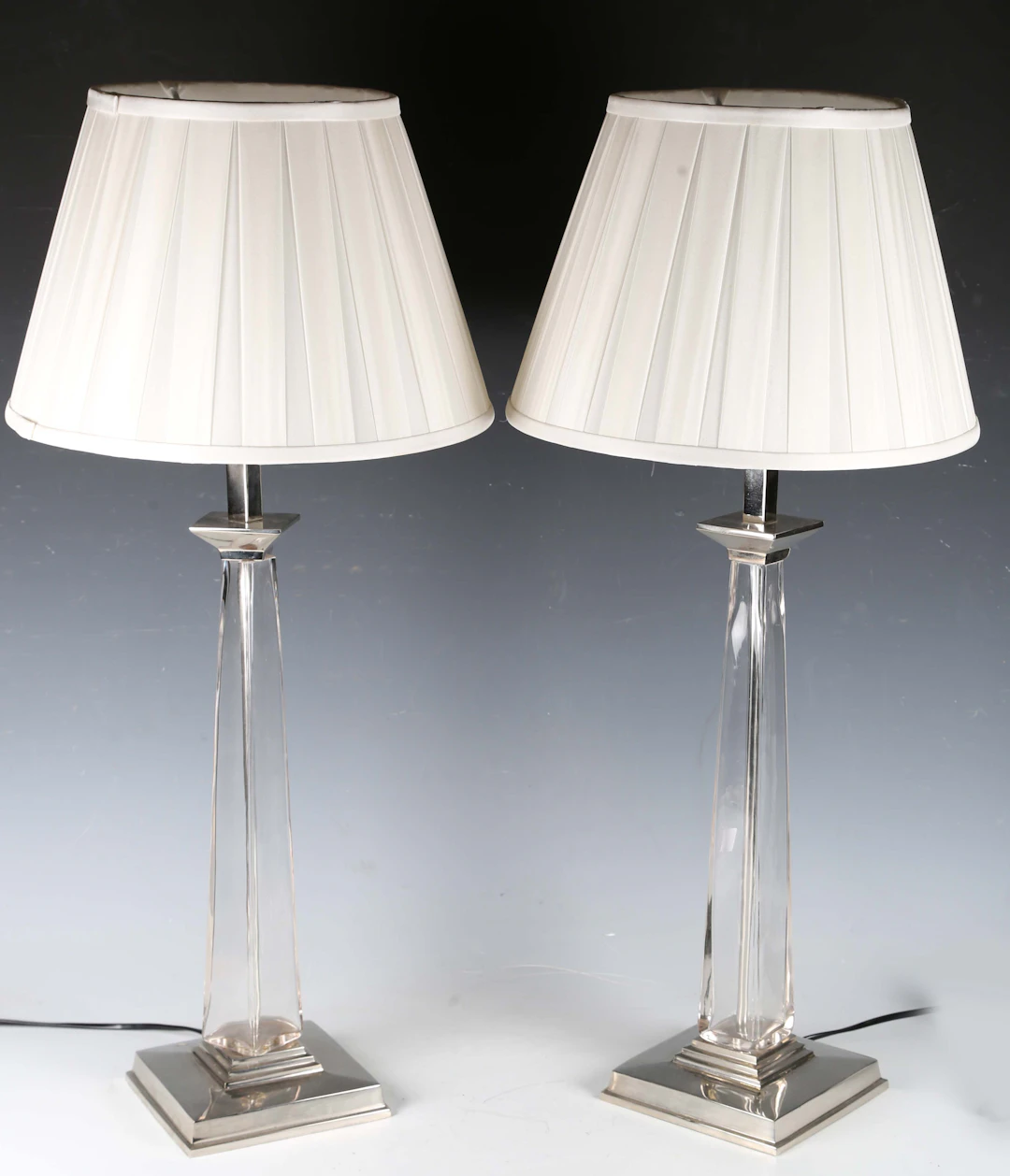 A pair of modern glass and plated metal table lamps with pleated fabric
